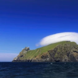 A rocky island coastline surrounded by deep blue water.